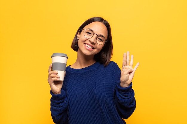 Joven mujer latina sonriendo y mirando amistosamente, mostrando el número cuatro o cuarto con la mano hacia adelante, contando hacia atrás