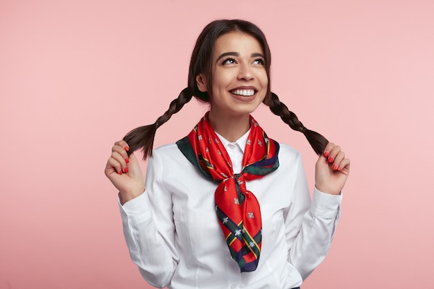 Foto joven mujer latina sonriendo y sosteniendo sus colas de caballo