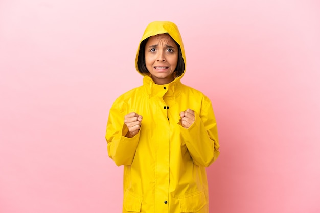 Joven mujer latina vistiendo un abrigo impermeable sobre fondo aislado frustrado por una mala situación