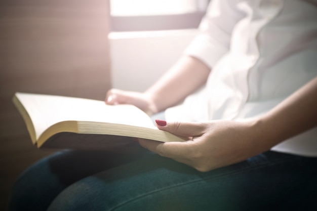 Foto joven mujer leyendo un libro cerca de la ventana