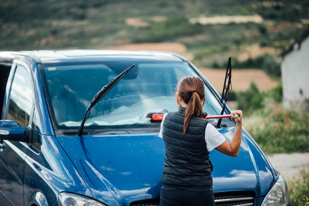 Foto joven mujer limpiando el parabrisas de la furgoneta azul