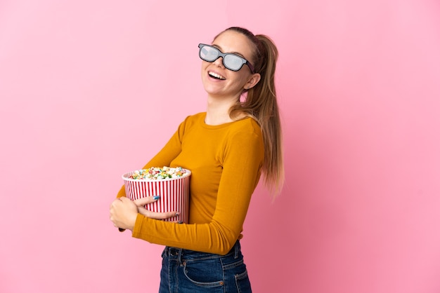 Joven mujer lituana aislada con gafas 3d y sosteniendo un gran cubo de palomitas de maíz