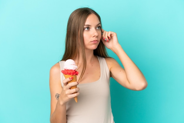 Joven mujer lituana con helado de cucurucho aislado sobre fondo azul teniendo dudas y pensando