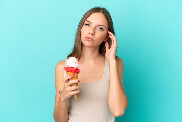 Joven mujer lituana con helado de cucurucho aislado sobre fondo azul teniendo dudas