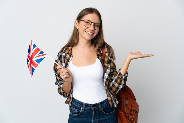 Joven mujer lituana sosteniendo una bandera del Reino Unido aislado sobre fondo blanco sosteniendo copyspace imaginario en la palma para insertar un anuncio