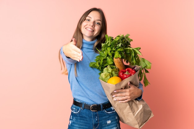 Joven mujer lituana sosteniendo una bolsa de compras un apretón de manos para cerrar un buen trato