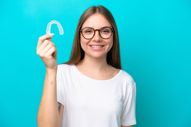 Joven mujer lituana sosteniendo llaves invisibles aisladas de fondo azul con expresión feliz