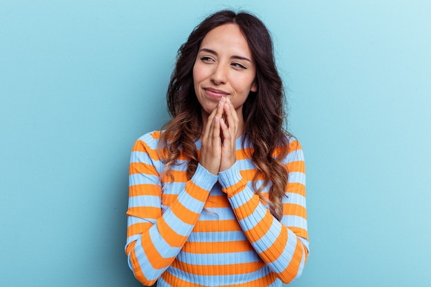 Joven mujer mexicana aislada sobre fondo azul haciendo un plan en mente, creando una idea.