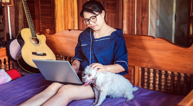 Una joven mujer moderna que trabaja en una computadora portátil mientras un lindo perro pequeño está al lado de su trabajo desde casa