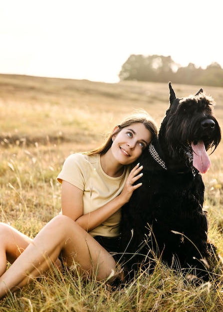 Joven mujer morena abrazando a su perro de raza schnauzer gigante