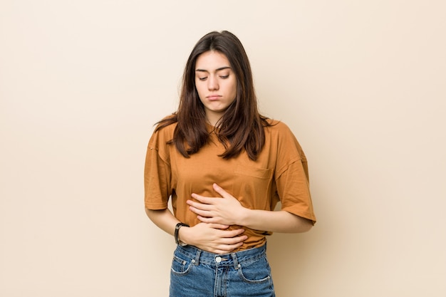 Joven mujer morena enferma, sufriendo de dolor de estómago, concepto de enfermedad dolorosa.