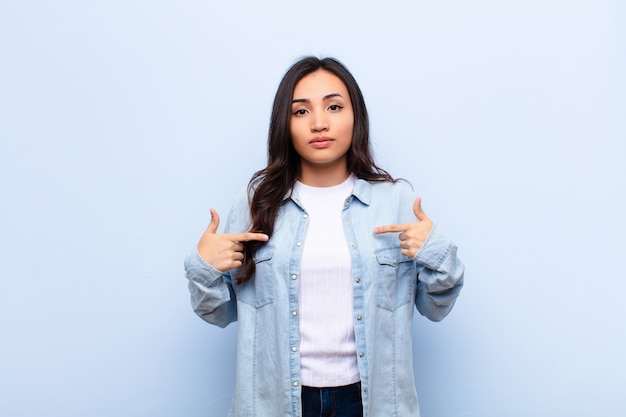 joven mujer morena positiva y casual apuntando al pecho con ambas manos