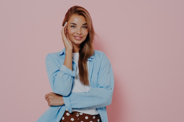 Joven mujer morena en ropa casual posando sobre fondo de estudio rosa aislado