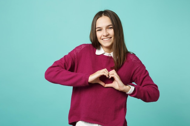 Joven mujer morena con ropa informal posando aislada en un retrato de estudio de fondo de pared turquesa verde azul. Gente emociones sinceras concepto de estilo de vida. Simulacros de espacio de copia. Pon las manos en el corazón.