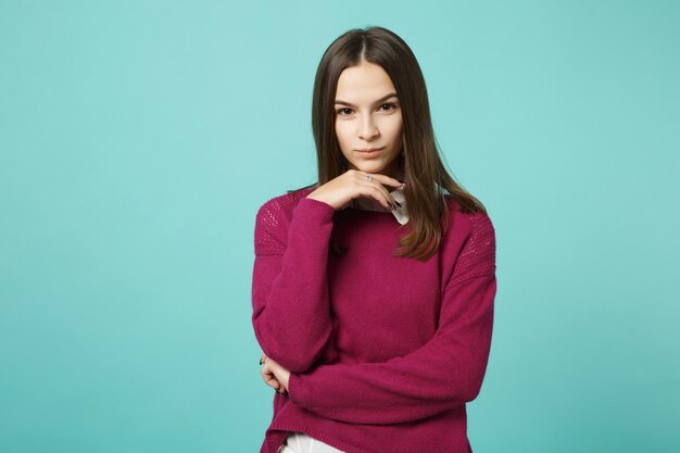 Joven mujer morena con ropa informal posando aislada en un retrato de estudio de fondo turquesa verde azul. Gente emociones sinceras concepto de estilo de vida. Simulacros de espacio de copia. ponga la mano apoyada en la barbilla.