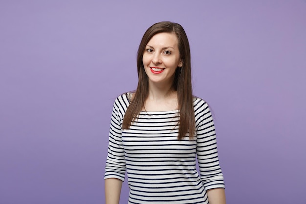 Joven mujer morena con ropa informal a rayas posando aislada en un retrato de estudio de fondo de pared púrpura violeta. Gente emociones sinceras concepto de estilo de vida. Simulacros de espacio de copia Mirando la sonrisa de la cámara