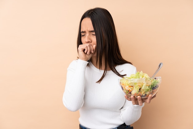 Foto joven mujer morena sosteniendo una ensalada sufre de tos y se siente mal