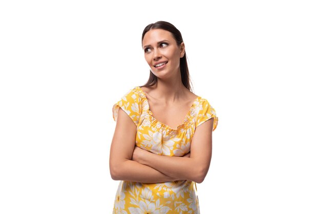 Joven mujer morena vestida con una camiseta amarilla de verano sobre un fondo blanco