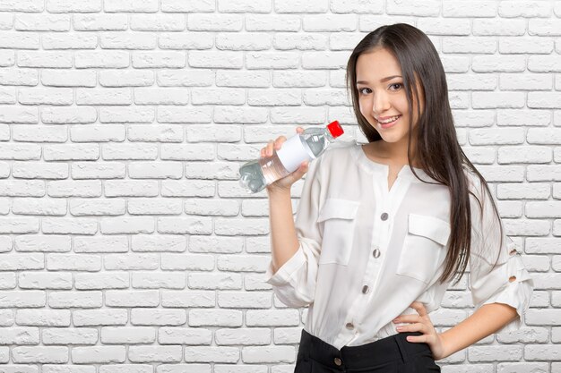 Joven mujer mostrando una botella de agua