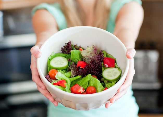 Joven mujer mostrando una ensalada