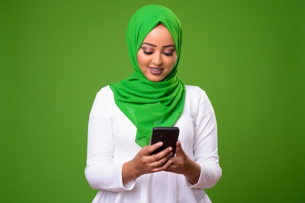 Joven mujer musulmana africana contra chroma key con pared verde