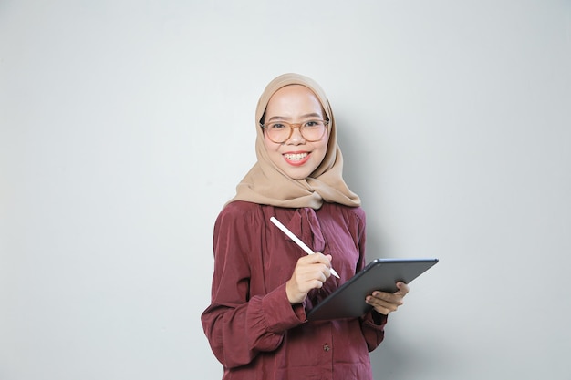 Joven mujer musulmana asiática con confianza usando anteojos y usando una tableta