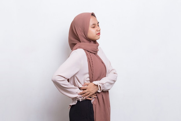 Joven mujer musulmana asiática que sufre de dolor lumbar y dolor lumbar en la cintura