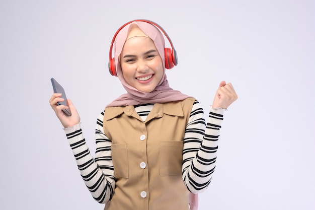 Una joven mujer musulmana beautifu usando auriculares sobre fondo blanco.
