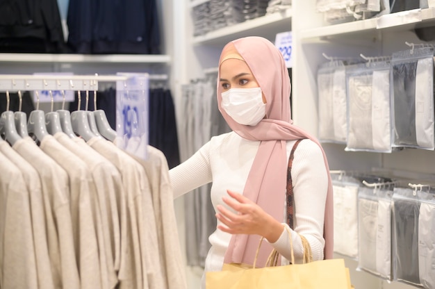 Una joven mujer musulmana con máscara protectora en el centro comercial