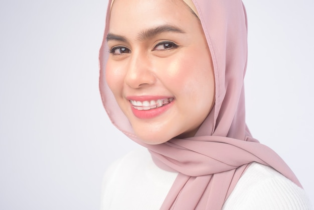 Una joven mujer musulmana con retenedor de colores para los dientes sobre blanco