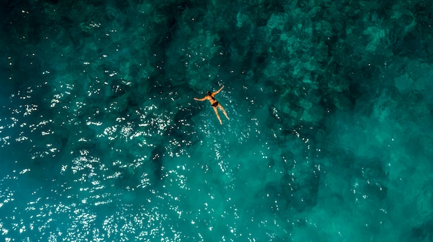 Joven mujer nadando en hermosa vista aérea del océano azul