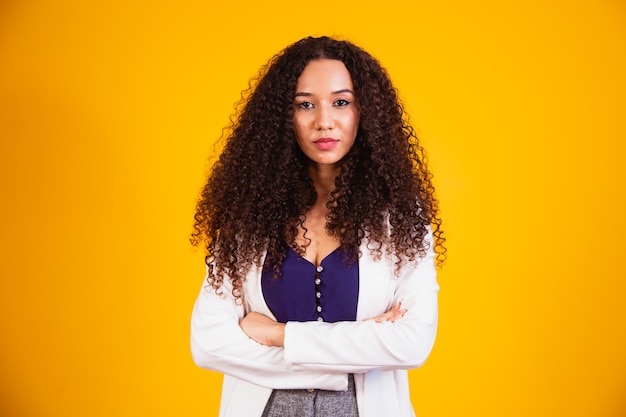 Joven mujer de negocios afro con los brazos cruzados sonriendo mirando a la cámara.