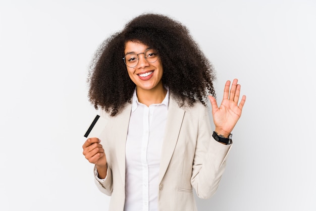 Joven mujer de negocios afro sosteniendo una tarjeta de crédito y mostrando el número cinco con los dedos