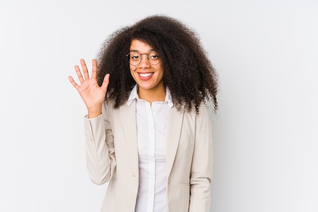Joven mujer de negocios afroamericana sonriendo alegre mostrando el número cinco con los dedos.