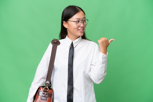 Joven mujer de negocios asiática sobre un fondo aislado apuntando hacia un lado para presentar un producto