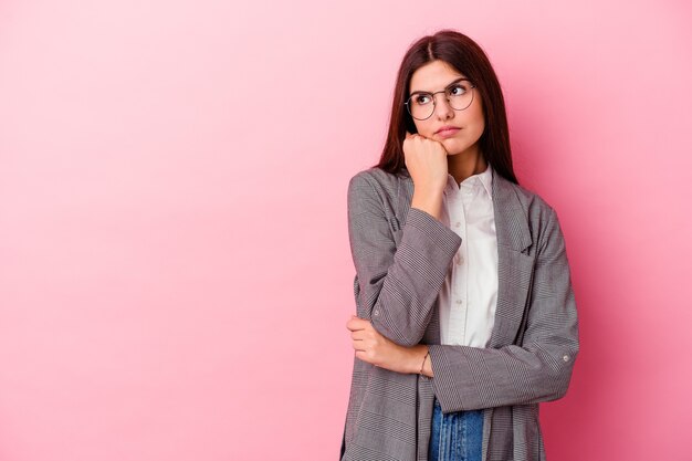 Joven mujer de negocios caucásica aislada sobre fondo rosa que se siente triste y pensativa, mirando el espacio de la copia.