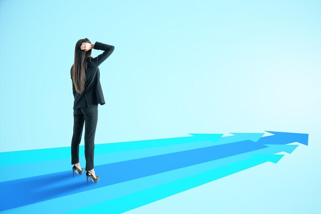 Joven mujer de negocios europea atractiva con flechas azules en un fondo claro con un lugar simulado dirección del camino y concepto de éxito