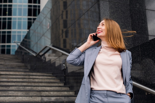Joven mujer de negocios feliz hablando por teléfono en la de un edificio de oficinas.