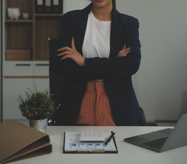 Joven mujer de negocios feliz usando computadora en una oficina moderna con colegas elegante hermosa gerente sonriente trabajando en proyectos financieros y de marketing bebiendo té o café de una taza
