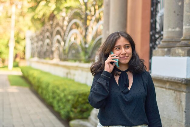 Joven mujer de negocios hispana en la ciudad usando un teléfono inteligente Personalidad exitosa