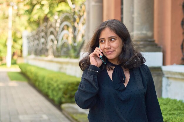 Joven mujer de negocios hispana en la ciudad usando un teléfono inteligente Personalidad exitosa