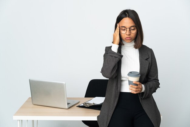 Joven mujer de negocios latina que trabaja en una oficina aislada sobre fondo blanco con dolor de cabeza