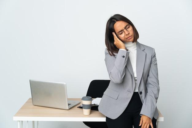 Joven mujer de negocios latina que trabaja en una oficina aislada sobre fondo blanco con dolor de cabeza