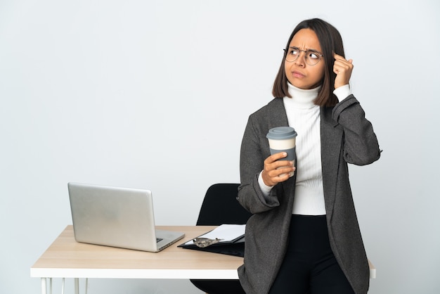 Joven mujer de negocios latina que trabaja en una oficina aislada sobre fondo blanco con dudas y pensamiento