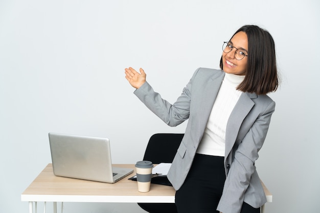 Foto joven mujer de negocios latina que trabaja en una oficina aislada sobre fondo blanco extendiendo las manos hacia el lado para invitar a venir