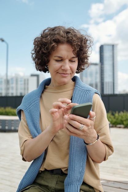 Foto joven mujer de negocios mirando la pantalla de su teléfono inteligente mientras aumenta el volumen de la imagen