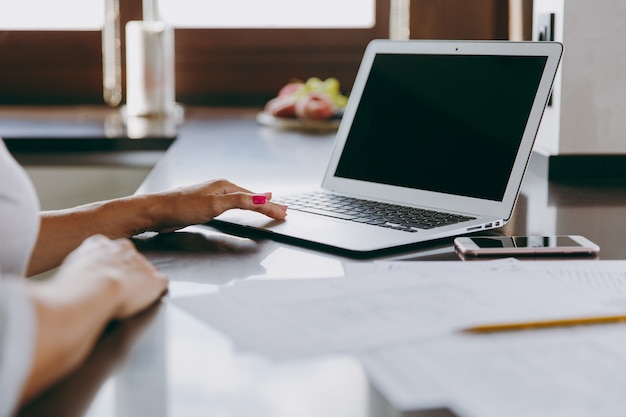 La joven mujer de negocios moderna que trabaja con documentos y portátil en casa