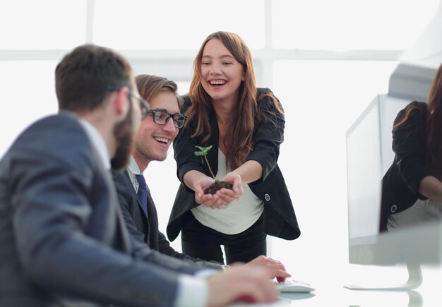 Joven mujer de negocios muestra brotes frescos del equipo de negocios. El concepto de una startup