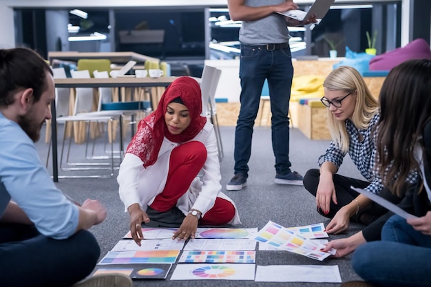 joven mujer de negocios musulmana negra que se reunió con su equipo de negocios multiétnico en el interior de la oficina moderna, presentando nuevas ideas en el suelo