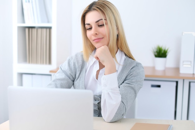 Joven mujer de negocios o estudiante sentada en el lugar de trabajo de la oficina con computadora portátil. Concepto de negocio en casa.